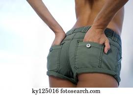 Young woman in shorts, hands in pocket, rear view