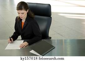 Businesswoman sitting at a desk and signing documents