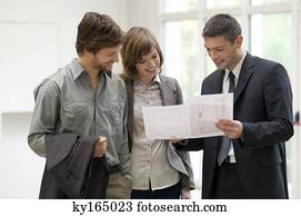 Real estate agent showing a blueprint to a couple