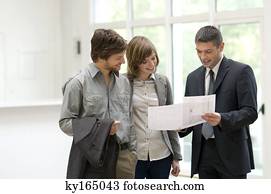Real estate agent showing a blueprint to a couple