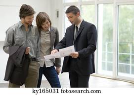 Real estate agent showing a blueprint to a couple