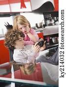 Boy playing a video game and his sister standing beside him