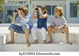Two children looking through binoculars with their friend sitting beside them