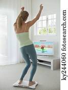 Woman doing step aerobics and watching TV