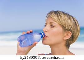 Woman drinking water on the beach