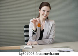Female real estate agent holding house keys in an office