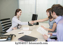Female real estate agent shaking hands with a couple