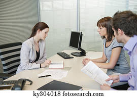 Female real estate agent showing a book to a couple