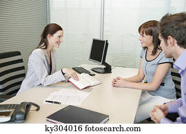 Female real estate agent showing a book to a couple