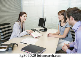 Female real estate agent showing a book to a couple