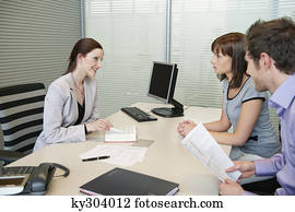 Female real estate agent showing a book to a couple