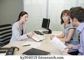 Female real estate agent showing a book to a couple