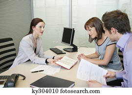 Female real estate agent showing a book to a couple