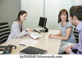 Female real estate agent showing a book to a couple
