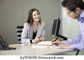 Man signing documents with a female real estate agent sitting in front of him