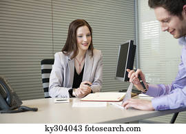 Man signing documents with a female real estate agent sitting in front of him