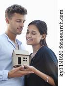 Cute young couple holding small model house