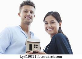 Portrait of a young couple holding a small model house