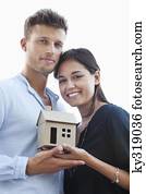 Portrait of a young couple holding small model house