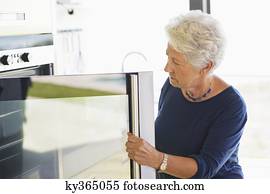 Senior woman looking into an oven