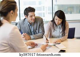 Couple signing documents with real estate agent