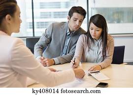 Couple signing documents with business executive