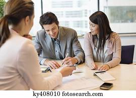 Couple signing documents with business executive