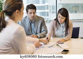 Couple signing documents with business executive