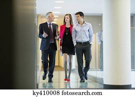 Business executives discussing in an office corridor Business executives discussing in an office corridor