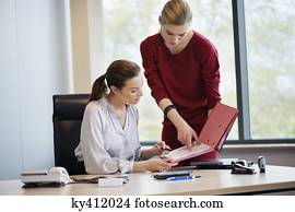 Businesswoman signing documents with her secretary