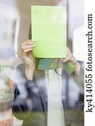 Businesswoman sticking memo notes on glass in an office