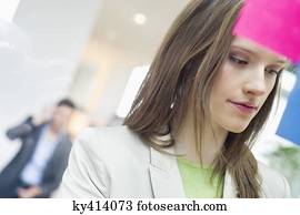 Businesswoman sticking memo notes on glass in an office