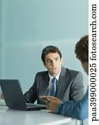 Businessman sitting at table, speaking to second man