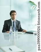 Businessman sitting at table with closed laptop and bottle of mineral water