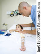 Boy lying in hospital bed, doctor taking pulse