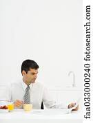 Man sitting at breakfast table, reading newspaper