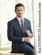 "Businessman sitting on edge of table, portrait"