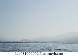 Calm sea with horizon over land in distance