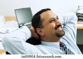 Businessman in office, hands behind head Businessman in office, hands behind head