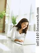 Woman lying on floor, using laptop, smiling Woman lying on floor, using laptop, smiling