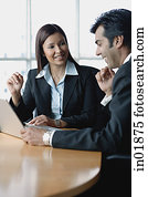 Businesswoman and businessman having a discussion, using laptop