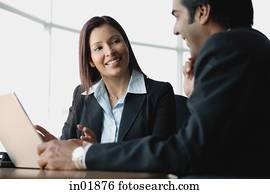 Businesswoman and businessman using laptop