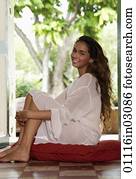 Young woman with long hair sitting on floor smiling Young woman with long hair sitting on floor smiling