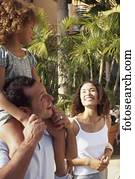 Daughter sitting on her father's shoulders with her mother standing beside them