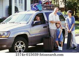 Portrait of a father standing with his son and daughter beside a car