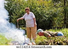 Senior couple trying to make a bonfire in the garden