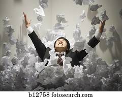 Businessman buried in mountain of crumpled papers