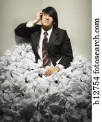 Businessman buried in mountain of crumpled papers