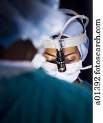 Female doctor in scrubs with head light in surgery Female doctor in scrubs with head light in surgery