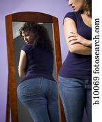 Young woman looking at her buttocks in the mirror